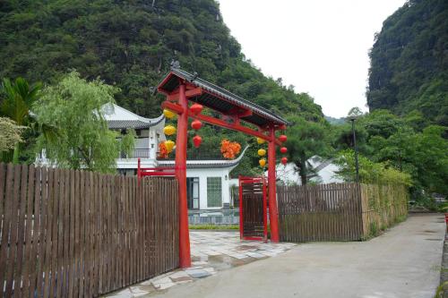 a red gate in front of a house with a fence at Happy Tam Coc Ecolodge in Ninh Binh
