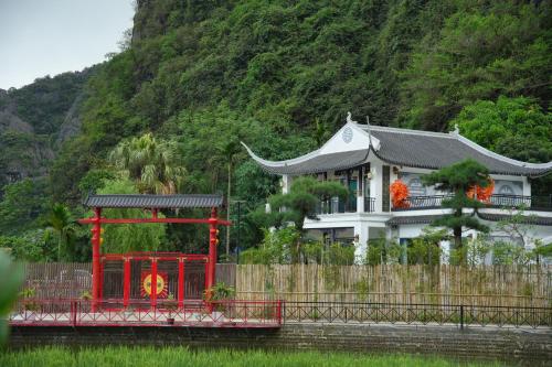 a building with a red structure in front of a house at Happy Tam Coc Ecolodge in Ninh Binh