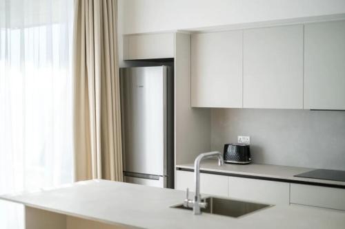 a white kitchen with a sink and a refrigerator at YAMAS Urban Living SEQUOIA Residence in Limassol