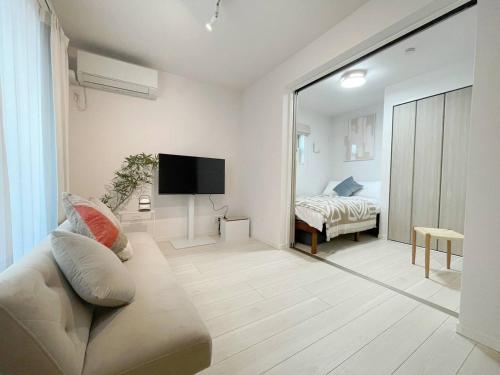 a living room with a couch and a tv and a bed at OPEN! TOKYO Kitasenju A Newly built stylish room! in Tokyo