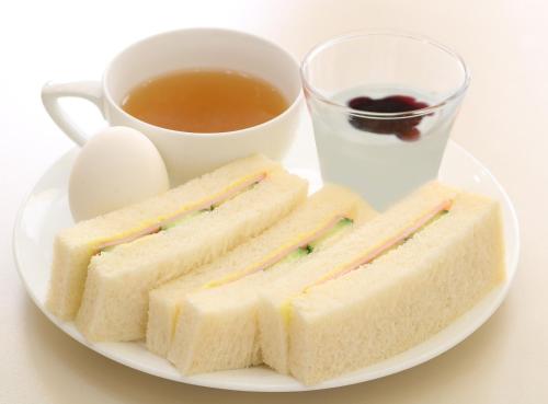 a plate with sandwiches and a cup of tea and a cup of coffee at Sotetsu Fresa Inn Shimbashi-Karasumoriguchi in Tokyo