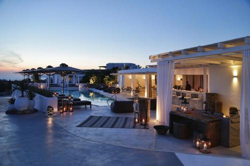 a patio with a bar and a pool at night at Livin Mykonos Hotel in Mikonos