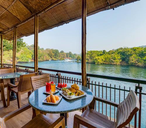 a table with food on a balcony with a view of a river at Silverbill Resorts-Redefining 5-Star Luxury in Dandeli in Ganeshgudi