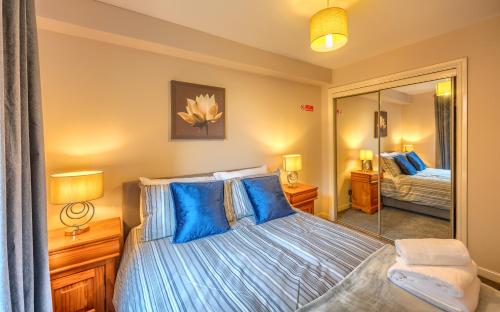 a bedroom with a bed with blue pillows and a mirror at Sharon Apartments Back Hilton in Aberdeen