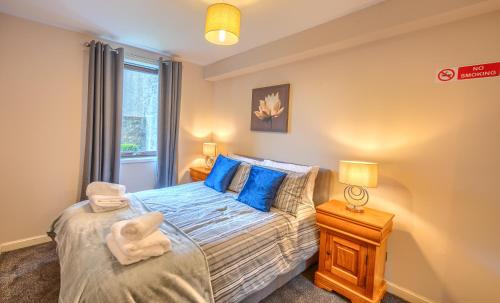 a bedroom with a bed with blue pillows and a window at Sharon Apartments Back Hilton in Aberdeen