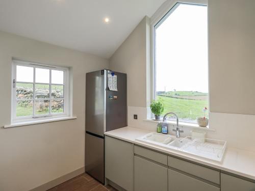 a kitchen with a refrigerator and a sink and a window at Old Cottage in Ulverston