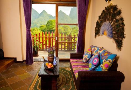 a living room with a couch and a large window at Yangshuo Coco Garden Hotel in Yangshuo
