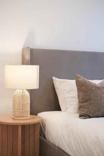 a bed with a lamp on a table next to it at 'Arch' 2 Bedroom Apt in the heart of Burwood, near everything in Sydney