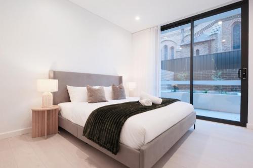 a bedroom with a large bed and a large window at 'Arch' 2 Bedroom Apt in the heart of Burwood, near everything in Sydney