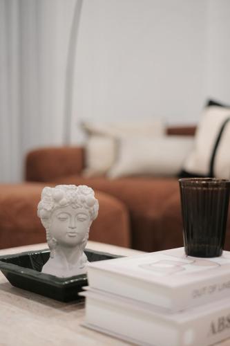 a statue on a table with a book and a cup at 'Arch' 2 Bedroom Apt in the heart of Burwood, near everything in Sydney