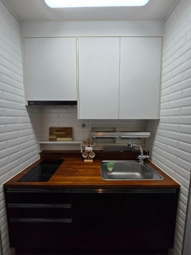 a small kitchen with a sink and white cabinets at Santiago 2nd in Busan