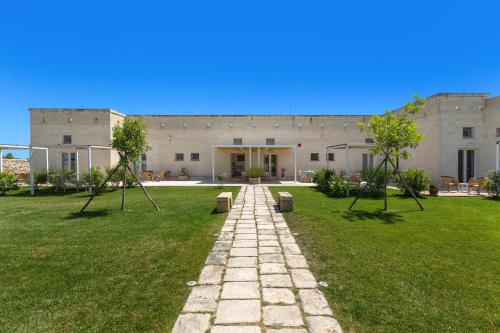 a building with a pathway in front of a yard at B&B Agricola Bellisario Ospitalità Rurale, Alimini Otranto in Conca Specchiulla