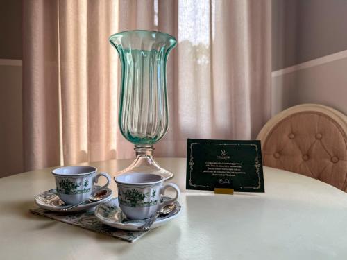 a glass vase sitting on a table with two cups at Villa Zane in Treviso
