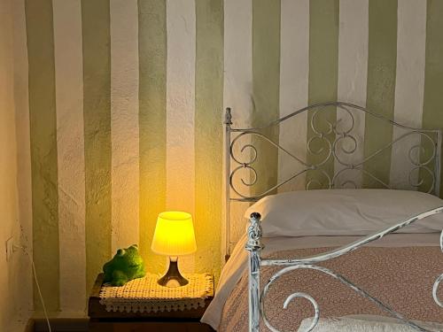 a bed with a lamp and a green and white striped wall at Borgo di Quarazzana holiday house with pool for groups Tuscany in Agnino