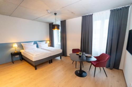 a hotel room with a bed and a table and a room at Das Adler in Markdorf