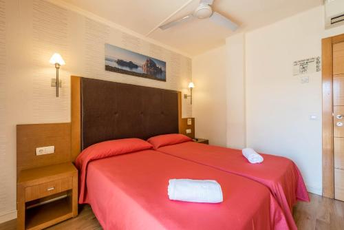 a bedroom with a red bed with a red blanket at Hostal Residencia Europa Punico in Ibiza Town