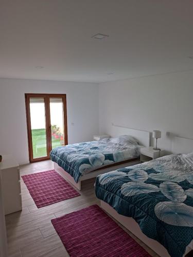 two beds in a white room with a window at Casa do Avô Carriço in Cantanhede