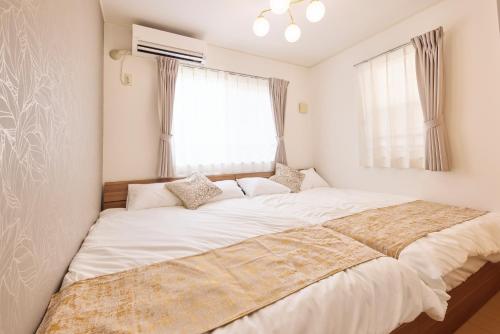 - une chambre avec un grand lit blanc devant une fenêtre dans l'établissement シャンブル南行徳201, à Tokyo