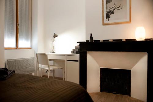 - une chambre avec un bureau et un lit avec une cheminée dans l'établissement Le meublé toulousain, à Toulouse