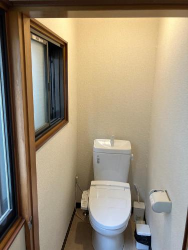 a small bathroom with a toilet and a window at ドラゴンinn in Aomori