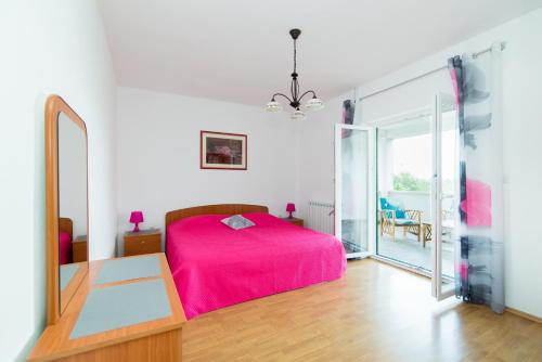a bedroom with a pink bed and a mirror at Apartments Cafe del Mar in Supetar