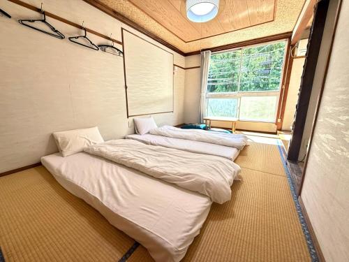 three beds in a small room with a window at Guesthouse KAZURABASHI in Miyoshi
