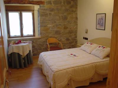 1 dormitorio con cama, mesa y ventana en Hostal Restaurante Arangoiti, en Yesa
