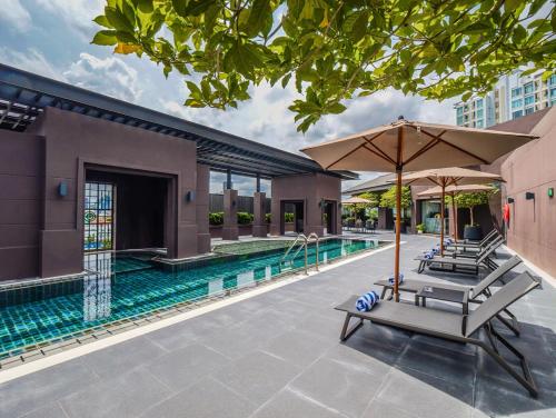 a swimming pool with two lounge chairs and an umbrella at Marriott Executive Apartments Bangkok, Sukhumvit 50 in Bangkok