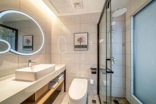 ein Badezimmer mit Toilette, Waschbecken und Spiegel in der Unterkunft GreenTree Inn Suzhou North Zhongshan Road Weiye Yingchun Plaza Business Hotel in Suzhou