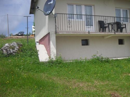 a house with a balcony with a table and chairs at Guest House Baranin Pitomine in Žabljak