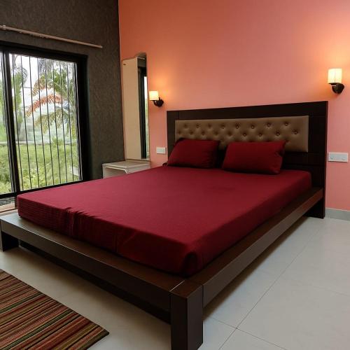 a bedroom with a large red bed with a large window at The Elite Villa 2 Bhk in Panchgani