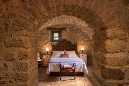 a bedroom with a bed in a stone wall at Mas Tulsà Casa Rural Girona in Riudellots de la Creu