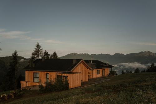 a wooden house on a hill with mountains in the background at Chalet Herol in Luson