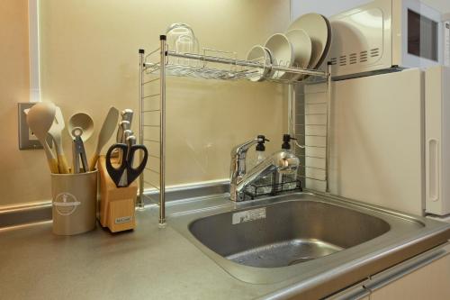 un comptoir de cuisine avec un évier et un micro-ondes dans l'établissement シャンブル南行徳201, à Tokyo