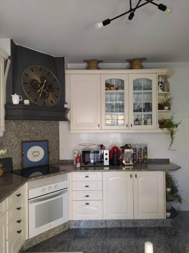 a kitchen with white cabinets and a clock on the wall at El Atico de Villalmar in Tui