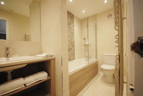 a bathroom with a sink and a tub and a toilet at Marlborough House - Guest House in Oxford