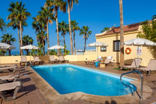 a pool with chairs and umbrellas at a resort at Tagoro Family & Fun Costa Adeje in Adeje