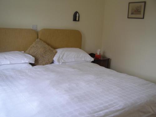 a bedroom with a white bed with two pillows at Church Hill Farm in Lighthorne