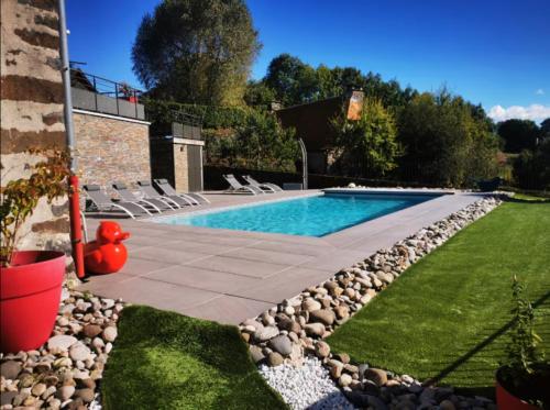 una piscina con rocce intorno e un cortile di Maison de Pruns - Piscine - Spacieuse - Calme a Saint-Santin-Cantalès