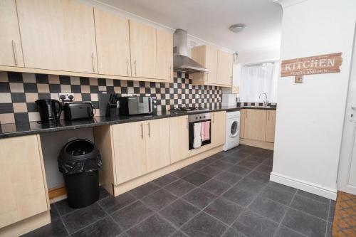 a kitchen with wooden cabinets and a washer and dryer at Family-Friendly 3-Bed House in Swansea in Swansea