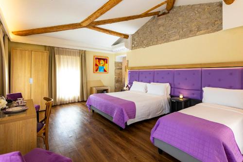 two beds in a hotel room with purple sheets at Hotel Corona in Spiazzi Di Caprino