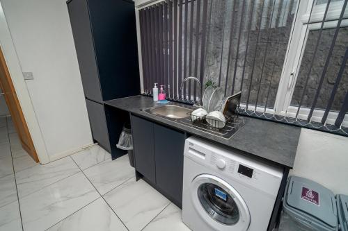 a kitchen with a sink and a washing machine at Spacious 3 Bed Home in the heart of Swansea in Swansea