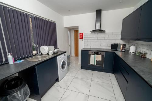 a kitchen with a sink and a washing machine at Spacious 3 Bed Home in the heart of Swansea in Swansea