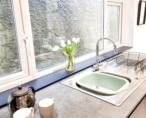 a kitchen sink with a vase of flowers in a window at Spacious 3 Bed Home in the heart of Swansea in Swansea
