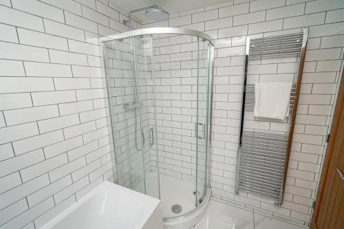 a white tiled bathroom with a shower and a sink at Spacious 3 Bed Home in the heart of Swansea in Swansea