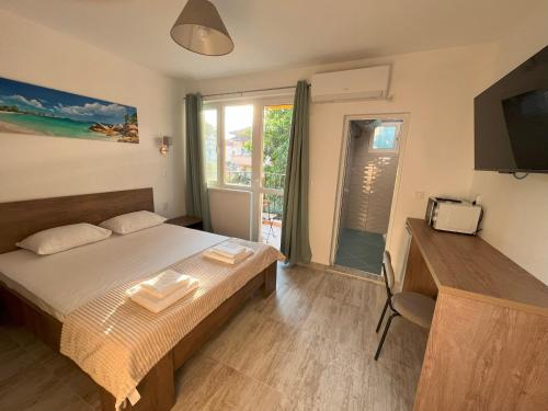 a bedroom with a bed and a television and a window at Семеен хотел Brizo in Ahtopol