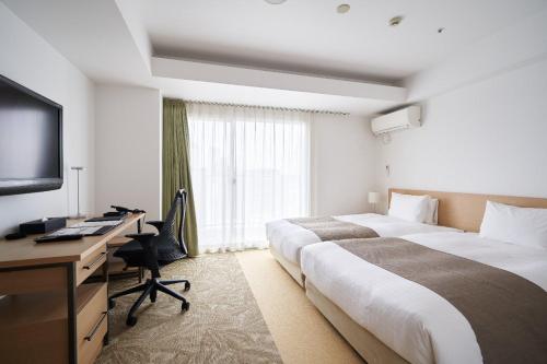 a hotel room with two beds and a desk and a television at Tokyu Stay Yotsuya in Tokyo