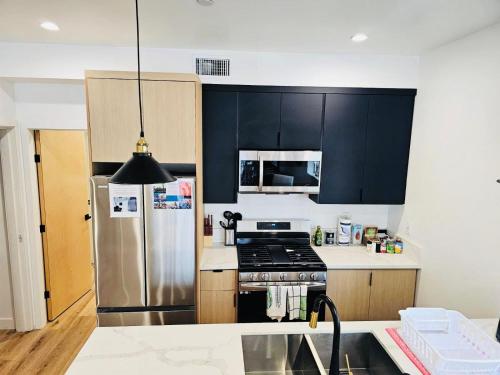 a kitchen with black cabinets and a stainless steel refrigerator at Hollywood Boutique Residences with Free Parking in Los Angeles