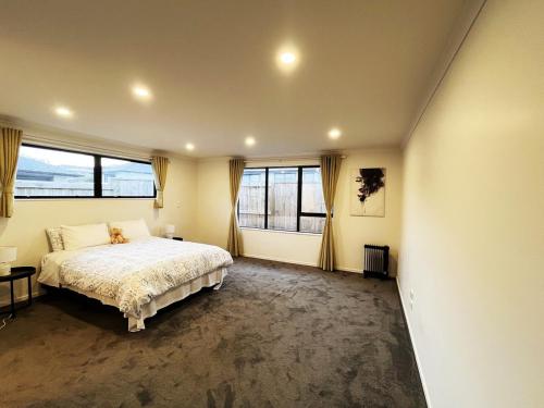 a bedroom with a large bed and large windows at 7th Heaven in Rotorua in Rotorua