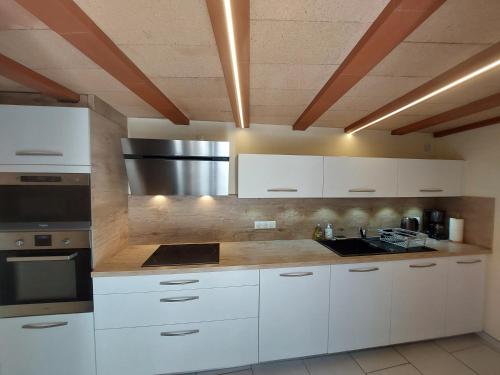 une cuisine avec des armoires blanches et un appareil en acier inoxydable dans l'établissement La Fontchaude (Cabrespine), à Cabrespine